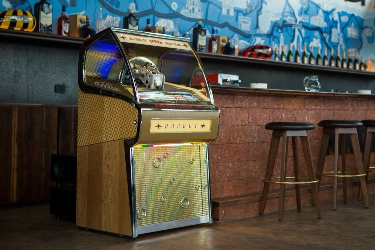 Rocket jukebox glowing beside the bar in a traditional pub