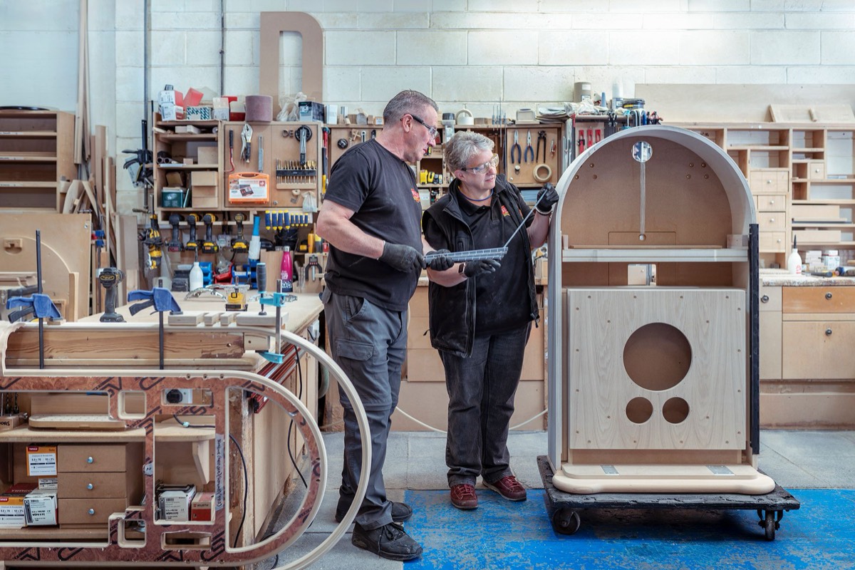 Two Sound Leisure team members inspecting a jukebox cabinet in the workshop