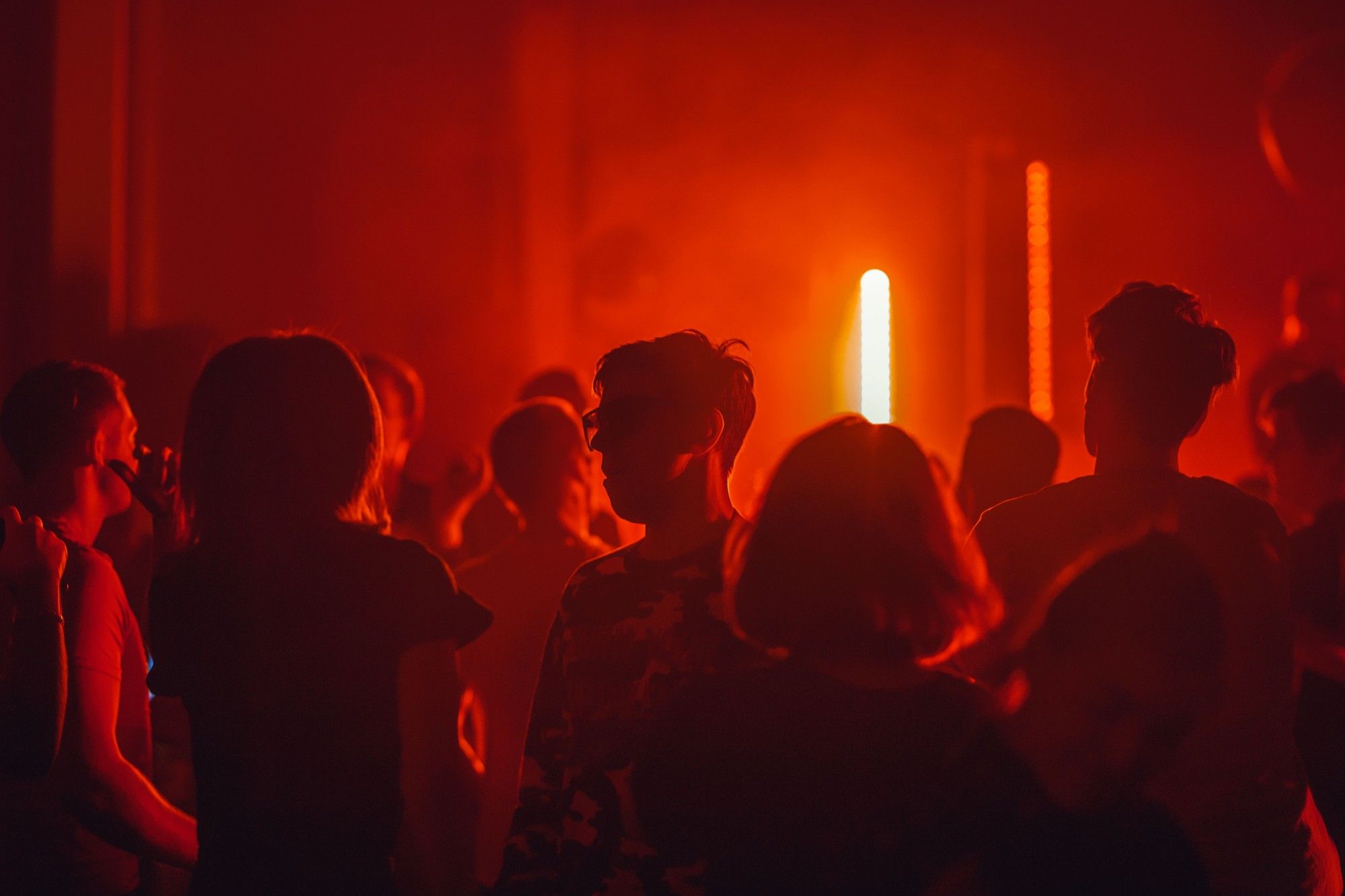 Crowd enjoying live music in a venue bathed in warm red light