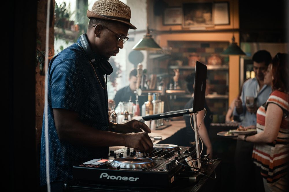 DJ mixing in a busy bar with customers in the background
